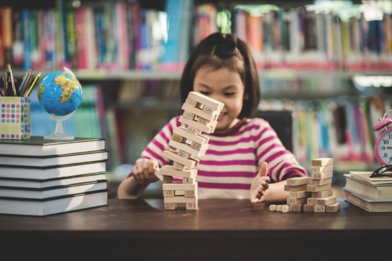 Portrait of kid cute asian girl happy to play blocks wood game at library